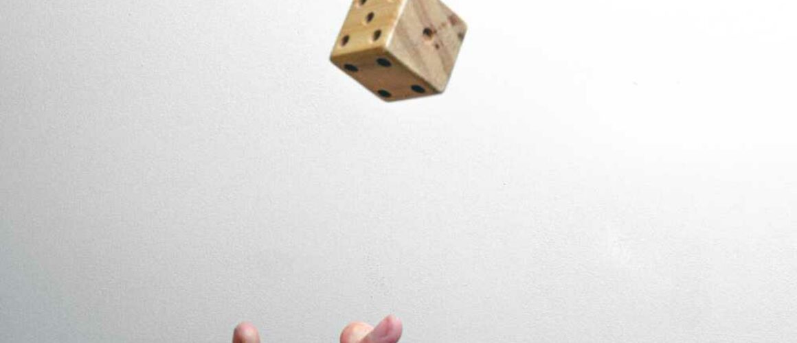 A hand throwing a six-sided die in the air on a white background