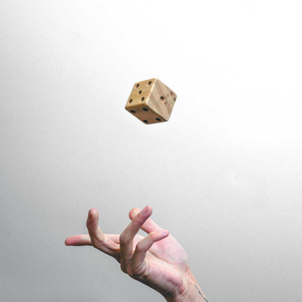 A hand throwing a six-sided die in the air on a white background